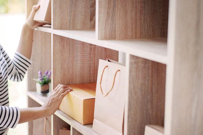 cropped shot of woman using wooden wall cubby to organize room - decluttering
