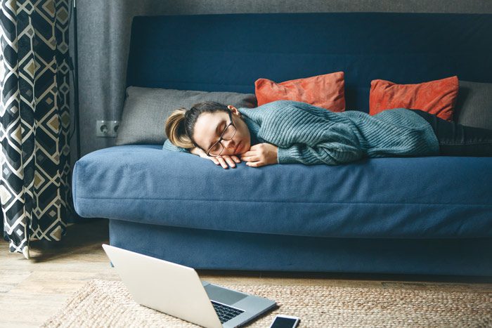 girl with glasses laying asleep on her couch with her laptop on the floor next to her - sleep